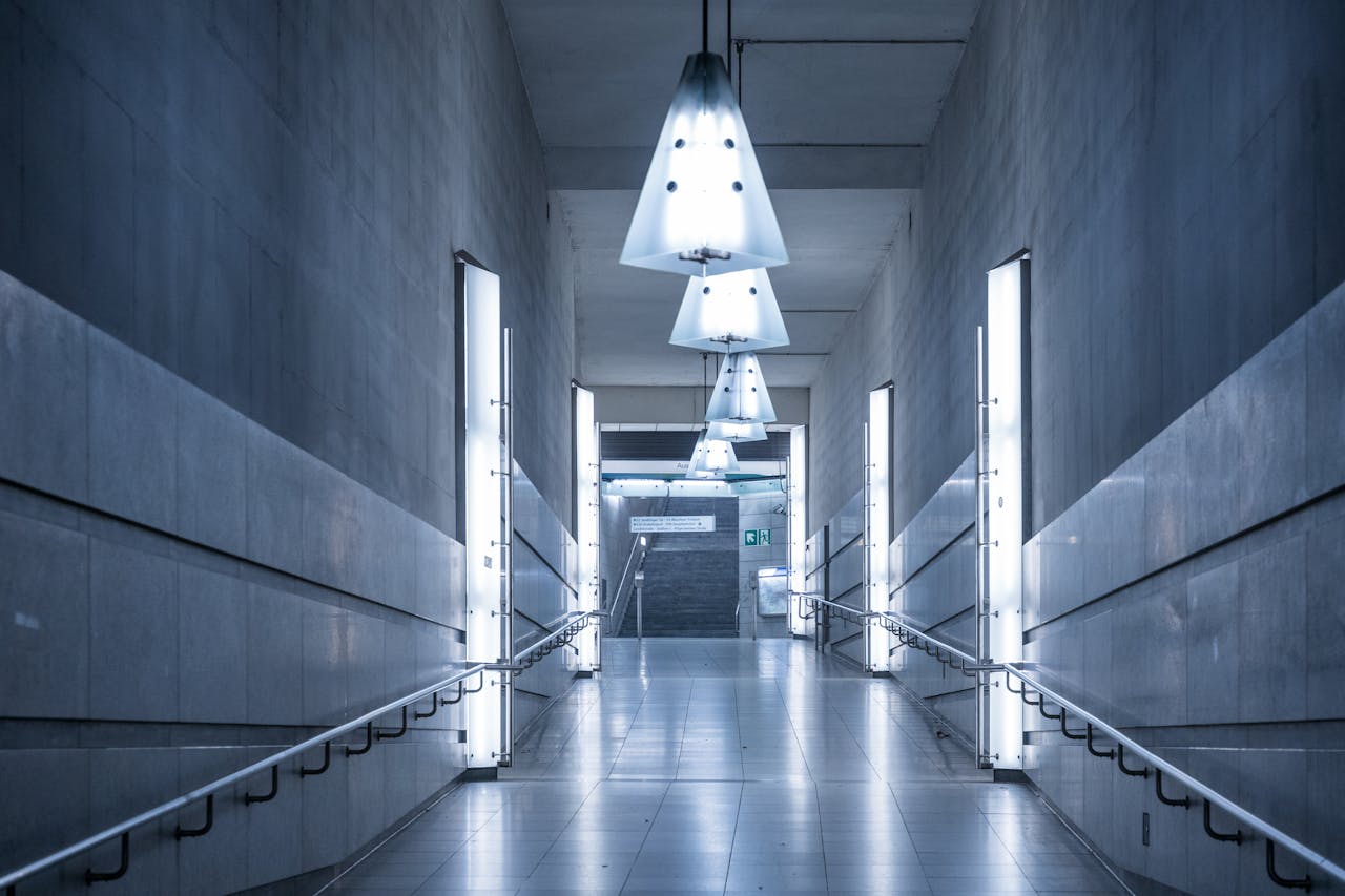 Explore a sleek, illuminated subway corridor with modern design elements and a calming blue tone.